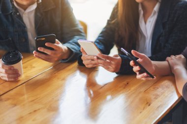 Birlikte otururken cep telefonunu kullanan ve ona bakan bir grup insan.