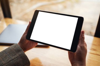 Siyah tabletli, beyaz ekranlı ve tahta masadaki laptoplu bir kadının görüntüsü. 