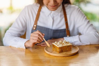 Kadın bir şef ahşap tepside ev yapımı havuçlu kek pişiriyor ve yiyor.