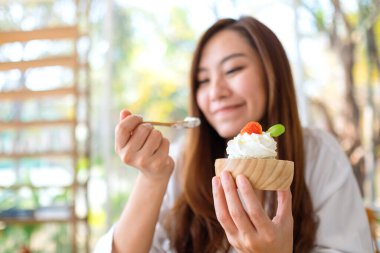 Güzel bir Asyalı kadının yakın plan görüntüsü restoranda dondurma yemekten zevk alır.