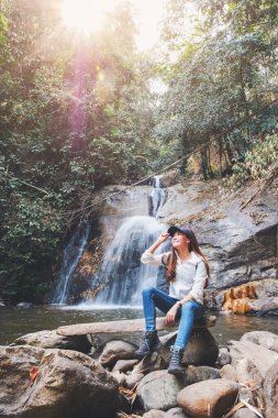 Ormanda şelalenin önünde oturan güzel bir Asyalı kadın.
