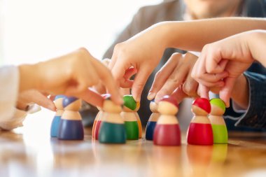 İnsanlar masadaki bir gruptan tahta figürleri seçip alıyor.