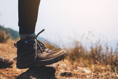 Dağın tepesinde yürüyüş botlarıyla bir kadının bacaklarının yakın görüntüsü.