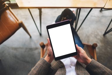 Boş beyaz masaüstü ekran ile siyah tablet bilgisayarını tutan bir kadının en üst görünüm görüntüsü 