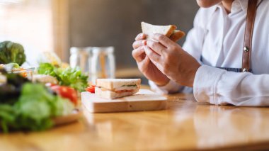 Mutfakta buğday ekmeği pişirip yiyen bir kadın şefin yakın plan görüntüsü.