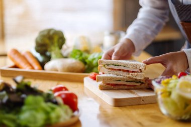 Mutfakta bir parça buğday sandviçi pişiren ve elinde tutan bir kadın şefin yakın plan fotoğrafı.