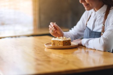 Kadın bir şef ahşap tepside ev yapımı havuçlu kek pişiriyor ve yiyor.