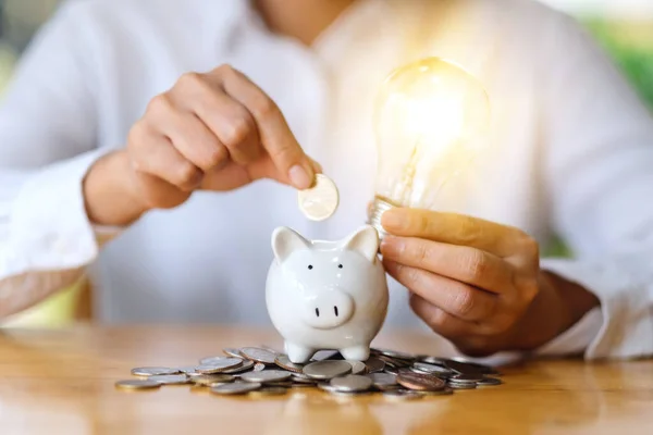 Eine Frau Legt Münzen Und Glühbirnen Über Ein Sparschwein Geld — Stockfoto