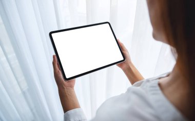 Yatak odasında içi boş beyaz masaüstü ekranlı siyah tabletli bir kadının görüntüsü. 