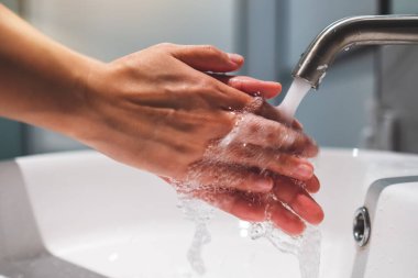 Kadınlar tuvaletteki musluğun altını temizleyip ellerini yıkıyor.