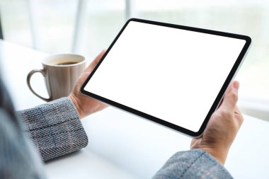 Masasında kahve fincanı olan siyah tabletli beyaz ekranlı bir kadının görüntüsü.