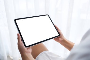 Siyah tabletli, beyaz ekranlı bir kadının sabah rahatlamış bir şekilde yatak odasında otururken görüntüsü.