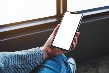 Boş beyaz masaüstü ekranlı cep telefonu tutan bir kadının görüntüsü 