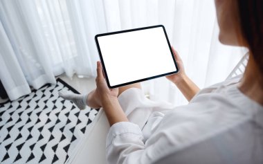 Siyah tabletli, beyaz ekranlı bir kadının sabah rahatlamış bir şekilde yatak odasında otururken görüntüsü.