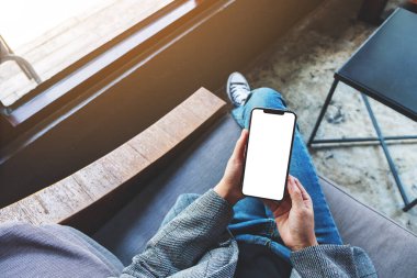 Beyaz masaüstü ekranlı siyah bir cep telefonu tutan bir kadının üst görünüm görüntüsü