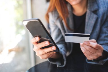 Cep telefonundan alışveriş yapan ve kredi kartı kullanan bir kadının yakın plan fotoğrafı.