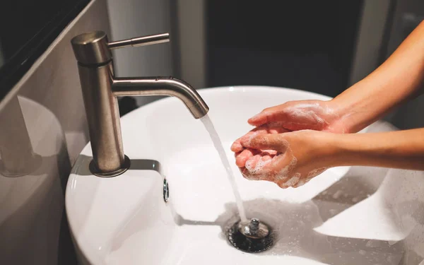 妇女在浴室的水龙头下用肥皂洗手 — 图库照片