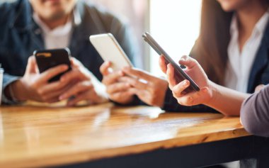 Birlikte otururken cep telefonunu kullanan ve ona bakan bir grup insan.
