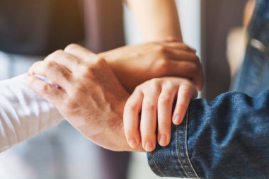 İnsanlar birlik ve takım çalışması konsepti için ellerini bir çemberin içine sokuyorlar.