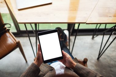 Boş beyaz masaüstü ekran ile siyah tablet bilgisayarını tutan bir kadının en üst görünüm görüntüsü 