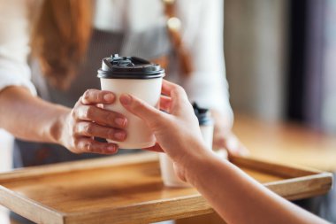 Bir garson, kafede müşteriye sıcak kahve ikram ediyor.