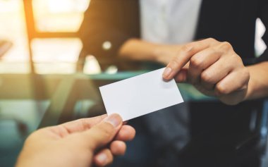 İki işadamı boş bir kartviziti tutuyor ve değiş tokuş ediyorlar. 