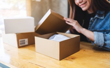 Güzel genç Asyalı bir kadın posta kutusunu teslim ve online alışveriş konsepti için alıyor ve açıyor.