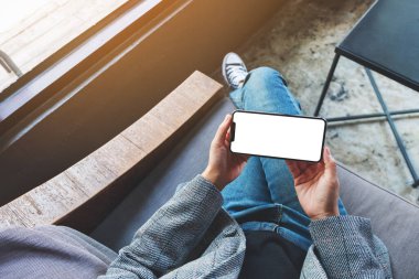 Beyaz masaüstü ekranlı siyah bir cep telefonu tutan bir kadının üst görünüm görüntüsü