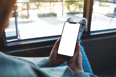 Kafede otururken elinde boş beyaz masaüstü ekran olan cep telefonu tutan bir kadının görüntüsü