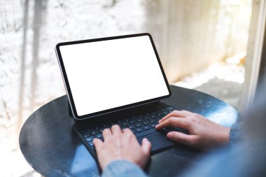Tablet klavyesinde boş beyaz masaüstü ekranı bir bilgisayar bilgisayarı olarak kullanan ve yazan bir kadının görüntüsü