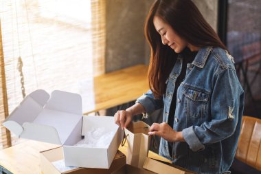 Güzel bir Asyalı kadının teslimat ve online alışveriş konsepti için evdeki alışveriş çantasının içini açıp içine baktığı yakın plan.