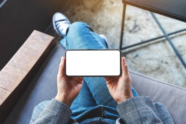 Beyaz masaüstü ekranlı siyah bir cep telefonu tutan bir kadının üst görünüm görüntüsü