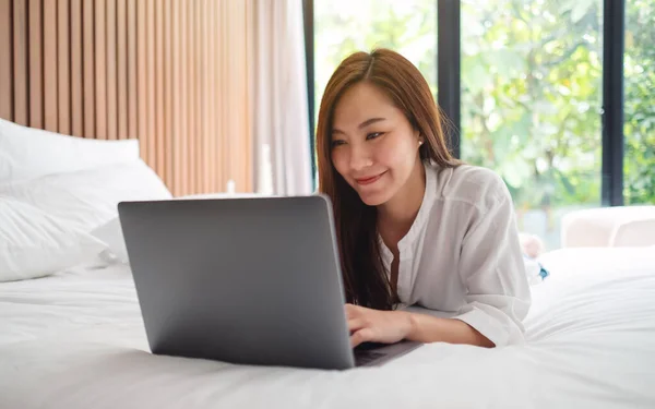 Piękna Azjatycka Kobieta Korzystająca Pracująca Laptopie Leżąc Białym Przytulnym Łóżku — Zdjęcie stockowe