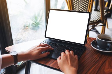 Tablet klavyesinde boş beyaz masaüstü ekran ile masada kahve fincanı olan bir bilgisayar bilgisayarı olarak yazan bir kadının görüntüsü