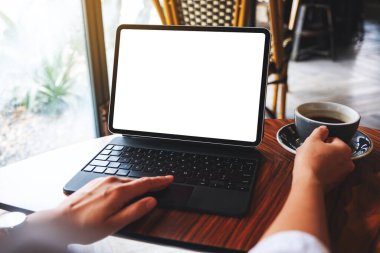 Kahve içerken bilgisayarın bilgisayar bilgisayarı olarak beyaz ekranı olan tablet dokunmatik ekranda dokunan bir kadının görüntüsü