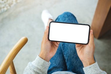 Boş beyaz masaüstü ekran ile cep telefonu tutan bir kadının en üst görünüm görüntüsü 