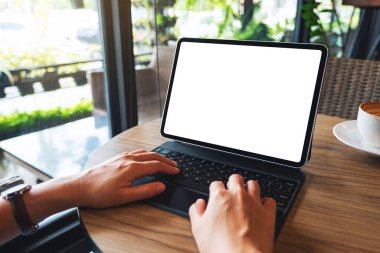 Tablet klavyesinde boş beyaz masaüstü ekranı bir bilgisayar bilgisayarı olarak kullanan ve yazan bir kadının görüntüsü