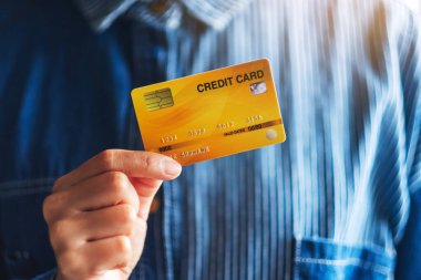 Kredi kartını tutan ve gösteren bir kadının yakın plan fotoğrafı.