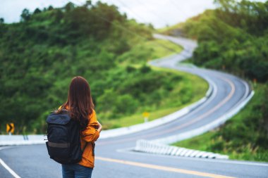 Bir dağ yolunda yürüyen sırt çantalı bir kadın gezginin arka plan görüntüsü