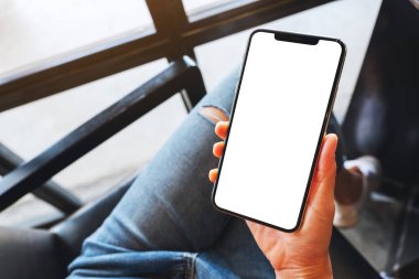 Boş beyaz masaüstü ekran ile cep telefonu tutan bir kadının en üst görünüm görüntüsü 