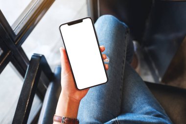 Boş beyaz masaüstü ekran ile cep telefonu tutan bir kadının en üst görünüm görüntüsü 