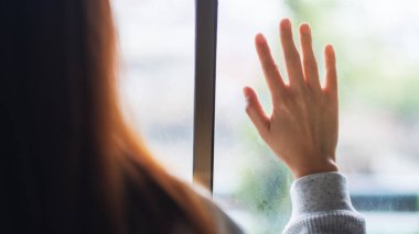 Dışarıya bakarken pencereye dokunan üzgün bir kadının arka plan görüntüsü