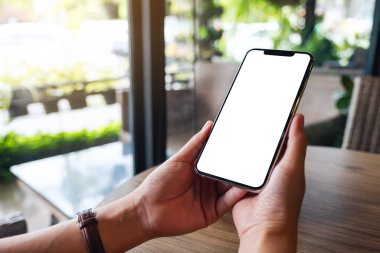 Boş beyaz masaüstü ekranlı cep telefonu tutan bir kadının görüntüsü 