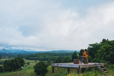 Açık havada kahve içen bir kadın güzel yeşil bir dağ ve doğa manzaralı.