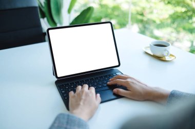 Ofiste bilgisayar bilgisayarı olarak boş beyaz masaüstü ekranı olan tablet klavyesinde yazı yazan ve kullanan bir kadının görüntüsü