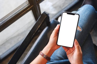Boş beyaz masaüstü ekran ile cep telefonu tutan bir kadının en üst görünüm görüntüsü 