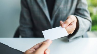 Ofiste iki işadamı boş kartvizit tutuyor ve değiş tokuş ediyor.