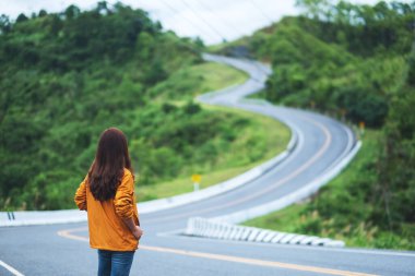 Yüksek dağlarda kıvrımlı ve dolambaçlı asfalt yolu olan genç bir kadın yolcunun dikiz görüntüsü