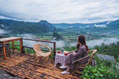 Balkonda sıcak kahve içen güzel bir kadının portresi. Dağlarda ve yeşil arka planda.