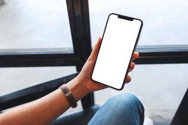 Boş beyaz masaüstü ekranlı cep telefonu tutan bir kadının görüntüsü 